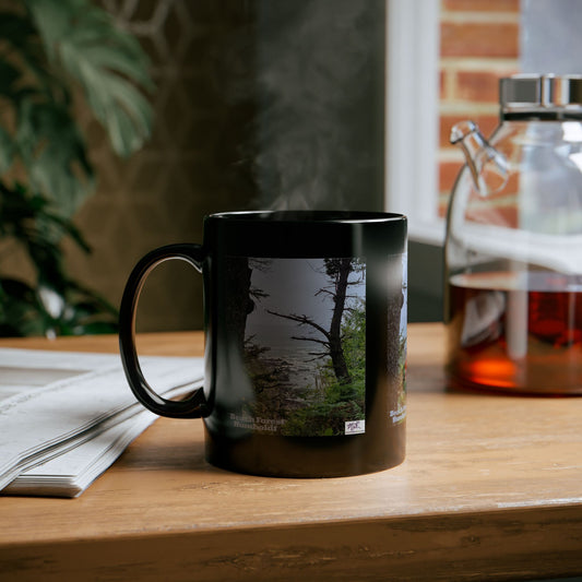 Black Mug 11oz - "Beach Forest Humboldt(tm)" - MiE Designs Shop. Sitka Spuce flank a trailhead leading down to rocky coastline below. Mug on desk